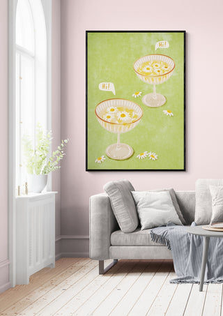 Framed "Hi" artwork by Raissa Oltmanns featuring two cocktail glasses, displayed above a light gray sofa.