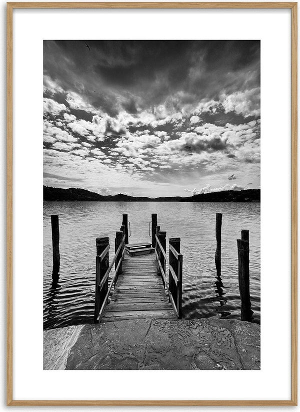 Black and white poster of a wooden bathing jetty extending into a calm lake under a dramatic cloudy sky.