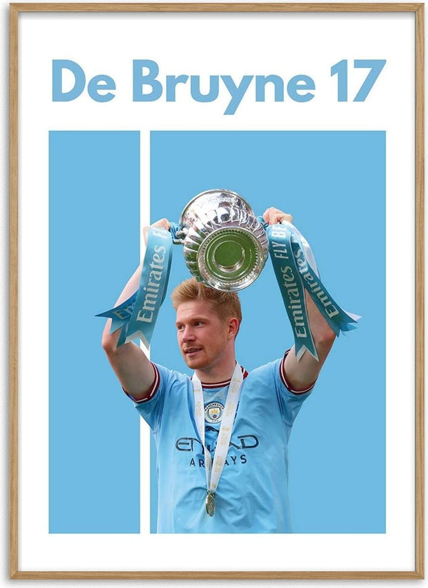 De Bruyne holding a trophy in Manchester City kit with "De Bruyne 17" text above on a blue football poster.