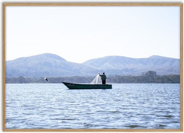 Fishermen Of Naivasha. (four) by Gloria Mwivanda - a fisherman holding his net in a green boat on a blue lake