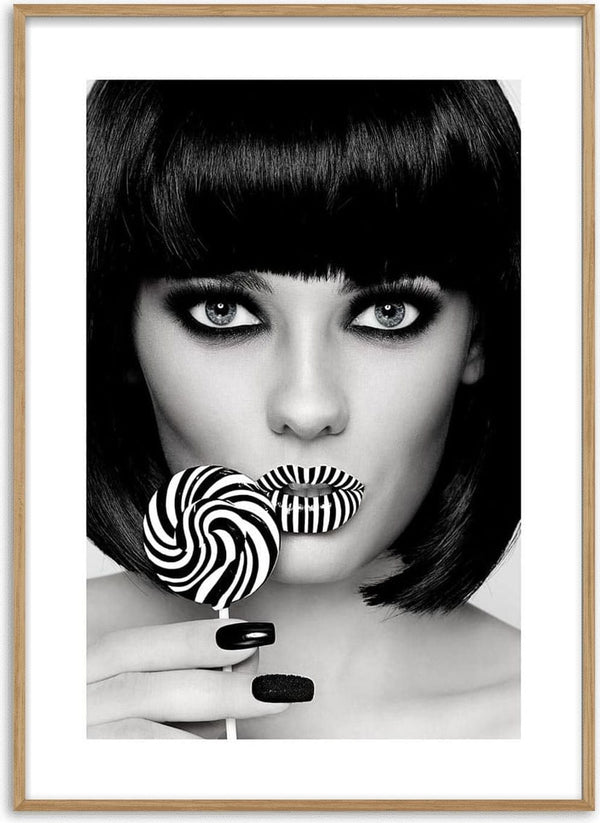 Stylish woman with bold makeup holding a matching black and white striped lollipop near her lips.