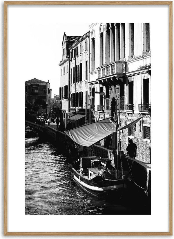 Black and white poster of a boat docked along a canal with historic Venetian buildings in the background.